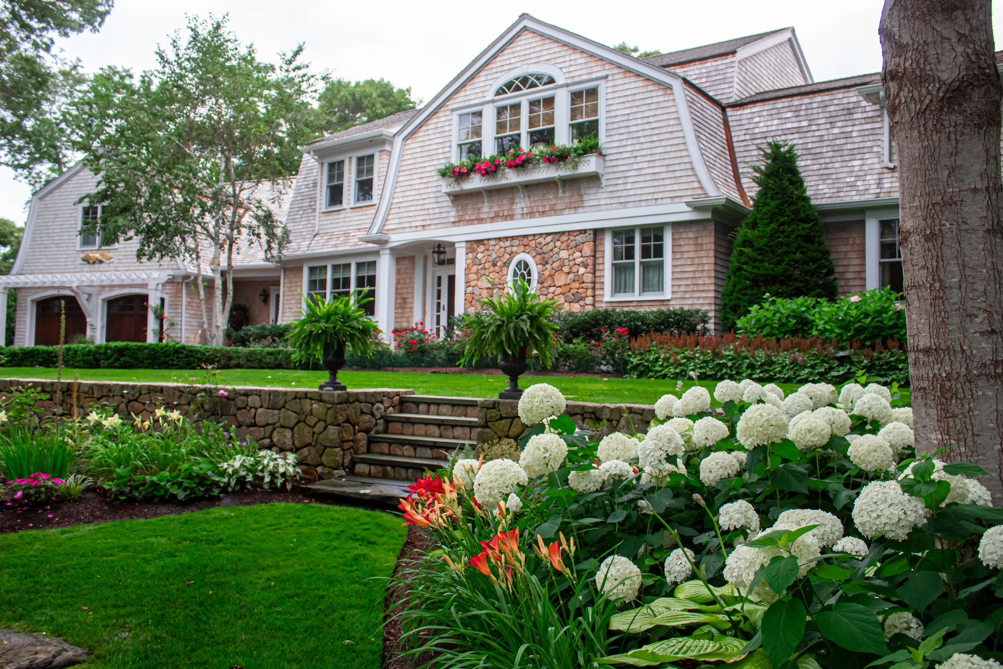 Cape Cod shingle estate with hydrangea beds, stone retaining wall and lily border